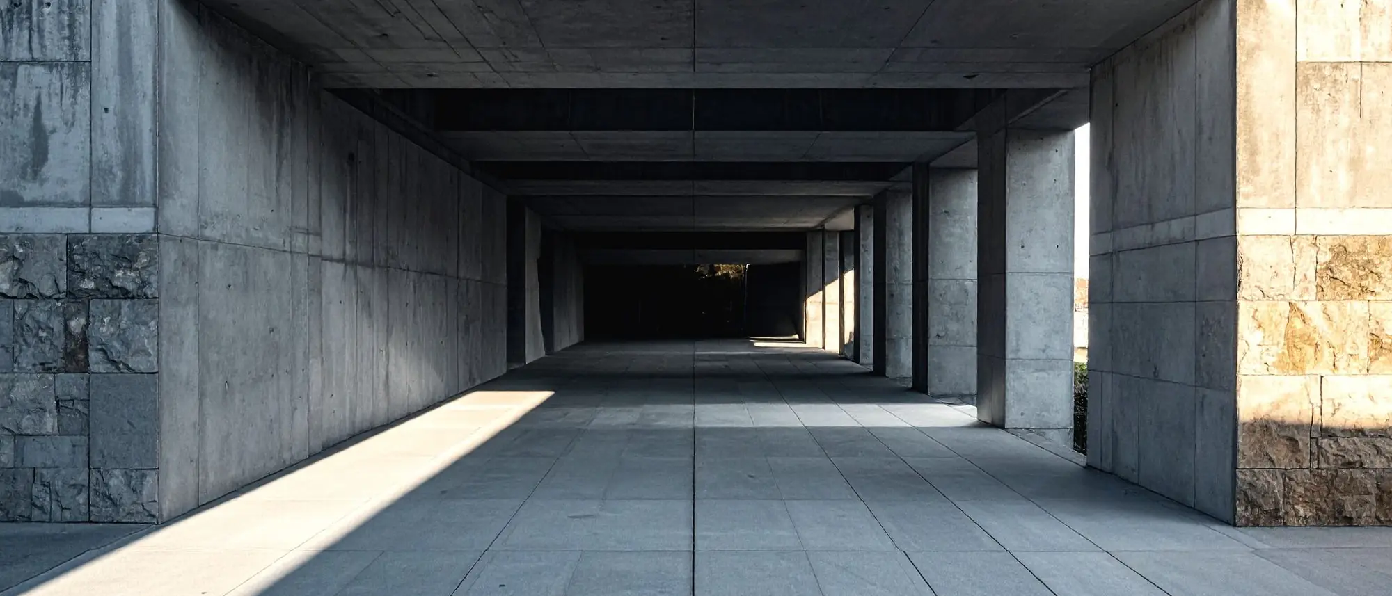 A long concrete corridor lit from one side, receding into shadow